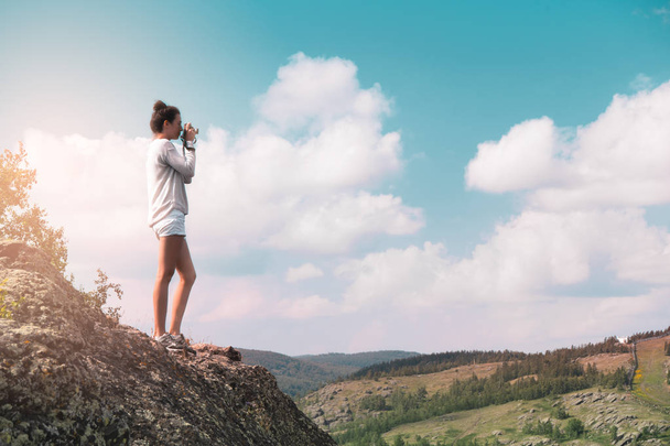woman photographer takes a picture of a mountain landscape on the camera - Foto, imagen