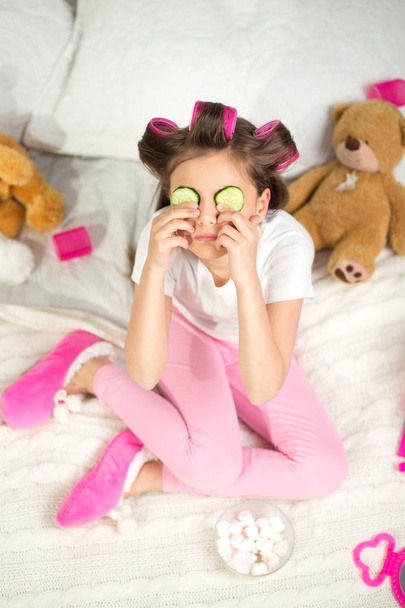 Little girl with cucumber slices on her eyes. - Valokuva, kuva