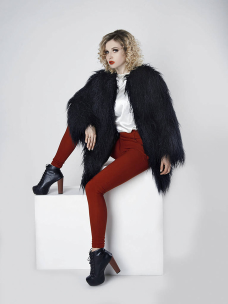 Beautiful young woman in fur.winter style  fashion.Beauty Girl with curly hairstyle sitting in studio - Fotoğraf, Görsel