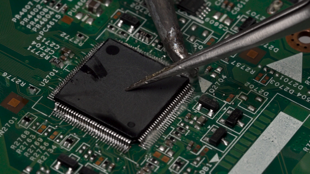 Desolder van oppervlak gemonteerde elektronische chip microprocessor met de soldeerbout van de printplaat. Weergave contacten van elektronische microprocessor. Close-up macro. - Video