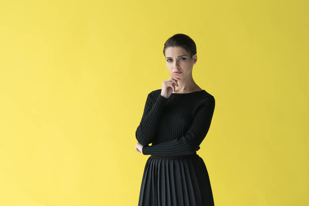 νεαρή όμορφη κοπέλα στέκεται με μαύρα ρούχα στο στούντιο - Φωτογραφία, εικόνα