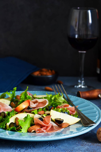 Salad with jamon, pears, blueberries and almonds. A glass of cold, red wine. Delicacy. - Valokuva, kuva