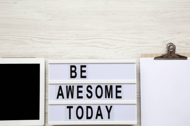 Work space with tablet, notepad and 'Be awesome today' word on lightbox over white wooden background, top view. From above, flat-lay, overhead. Copy space. - Photo, Image