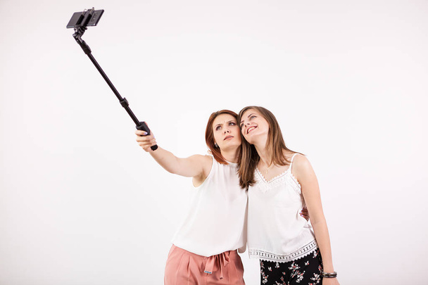 Deux belles jeunes femmes prenant un selfie avec un bâton de selfie
 - Photo, image