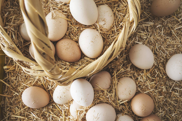 Φρέσκα ωμά αυγά σε ψάθινο καλάθι - Φωτογραφία, εικόνα