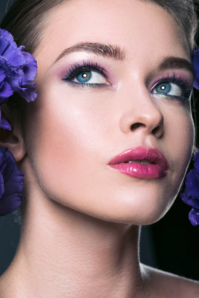 Close-up πορτρέτο του όμορφη νεαρή γυναίκα με μοντέρνα λουλούδια μακιγιάζ και eustoma - Φωτογραφία, εικόνα