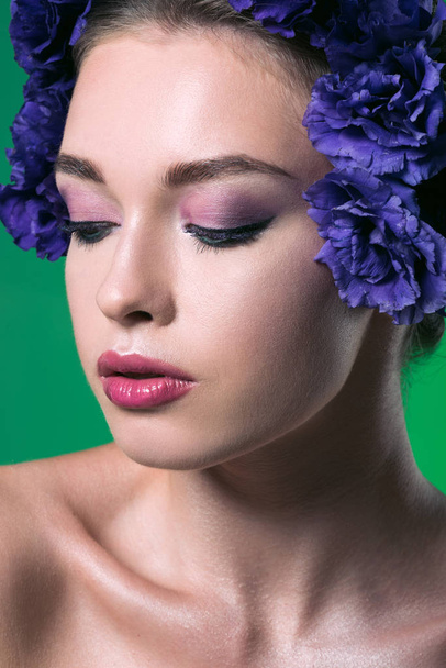 close-up portrait of beautiful young woman with eustoma flowers on head and closed eyes isolated on green - Photo, Image