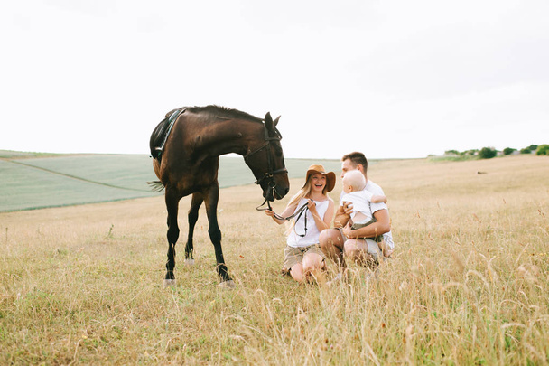 familia joven tener una diversión en el campo. Padres e hijos con un caballo en el campo
  - Foto, imagen