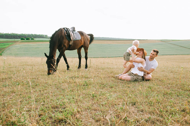 young family have a fun in the field. Parents and child with a horse in the field  - Foto, Bild