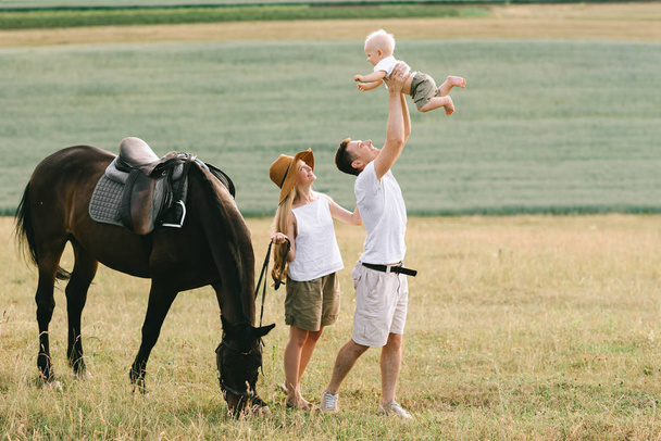 young family have a fun in the field. Parents and child with a horse in the field  - Fotó, kép