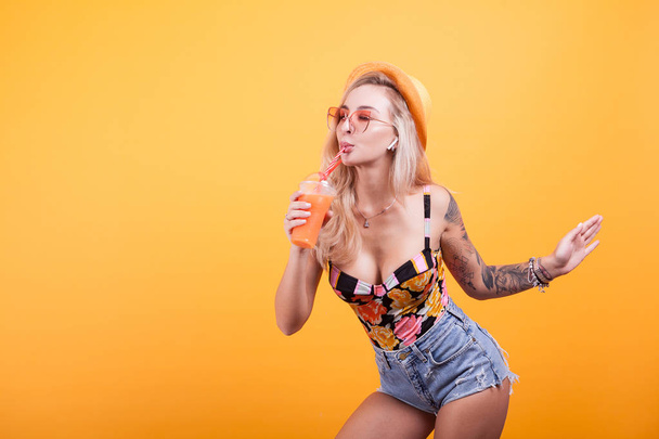 Красивая привлекательная женщина пьет апельсиновый сок в солнечных очках
 - Фото, изображение