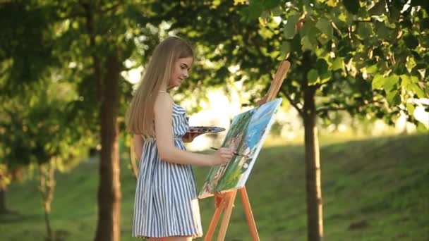 Mooi meisje kunstenaar is permanent in het park en houden palet met verf - Video