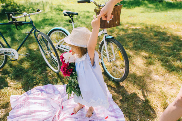 Happy little girl with peonies in park  - Foto, afbeelding