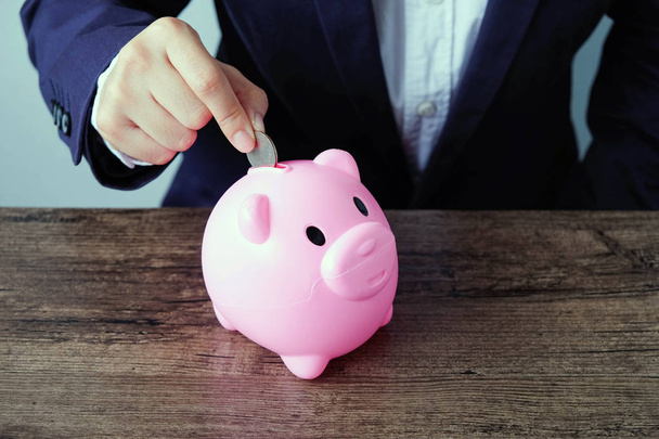 Hand of businessman insert coin into piggy bank.saving money concept - Foto, Imagen