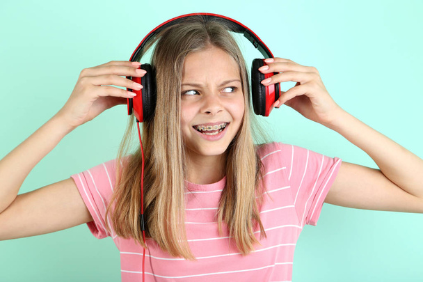 Beautiful young girl with headphones on mint background - Фото, зображення