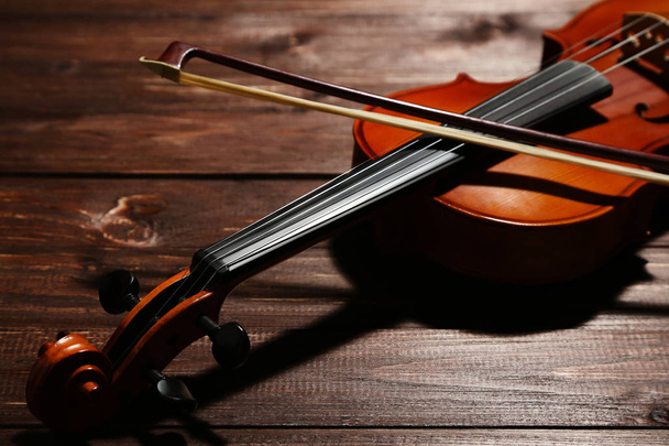 Violin with bow on brown wooden table - Φωτογραφία, εικόνα