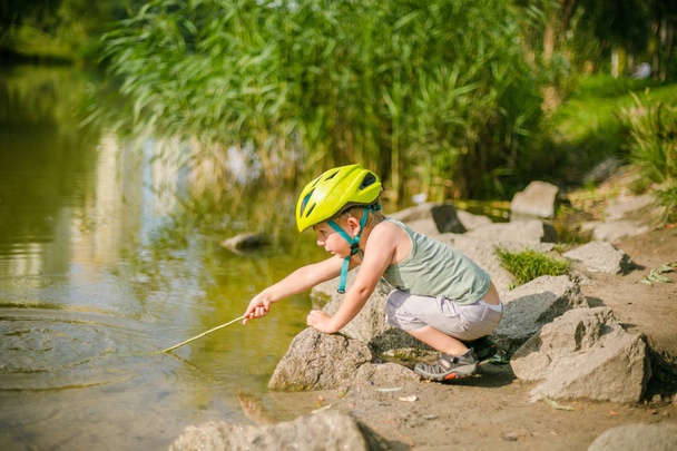 Menino brinca com água perto de um lago
 - Foto, Imagem