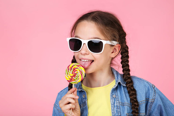 Young girl with lollipop and sunglasses on pink background - Photo, Image
