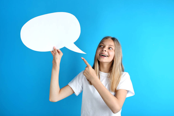 Young girl holding speech bubble on blue background - Photo, Image