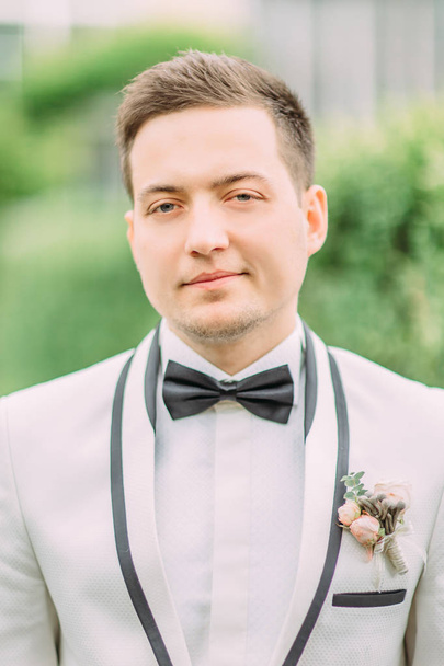 Close-up portrait of the handsome groom at the background of the garden. - Foto, afbeelding