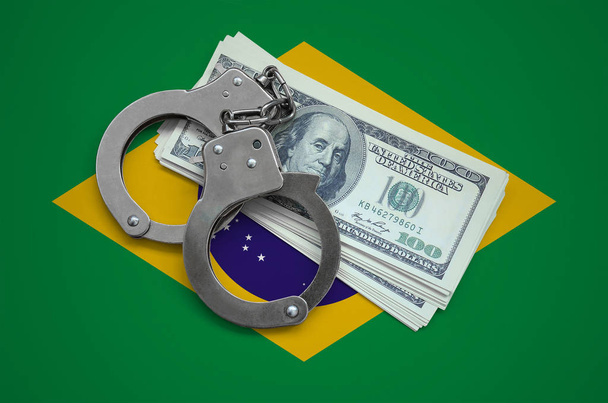 Bandera de Brasil con esposas y un paquete de dólares. Corrupción de divisas en el país. Delitos financieros
. - Foto, Imagen