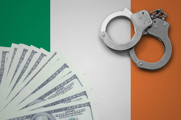 Ireland flag  with handcuffs and a bundle of dollars. The concept of illegal banking operations in US currency. - Photo, Image