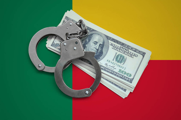 Flaga Beninu z kajdanek i pakiet dolarów. Waluty korupcji w kraju. Przestępstw finansowych. - Zdjęcie, obraz