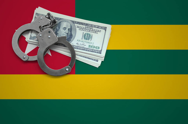 Togo bayrağı ile kelepçe ve a bohça-in dolar. Hukuk ve hırsızlık suçları kırılma kavramı. - Fotoğraf, Görsel