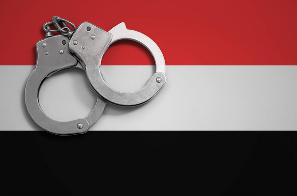 Jemen vlag en politie handboeien. Het concept van misdrijven en overtredingen in het land. - Foto, afbeelding