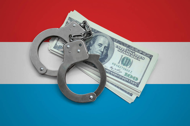 Luxemburg zászló bilincs és egy köteg-ból dollárok. Pénznem a korrupció az országban. Pénzügyi bűncselekmények. - Fotó, kép