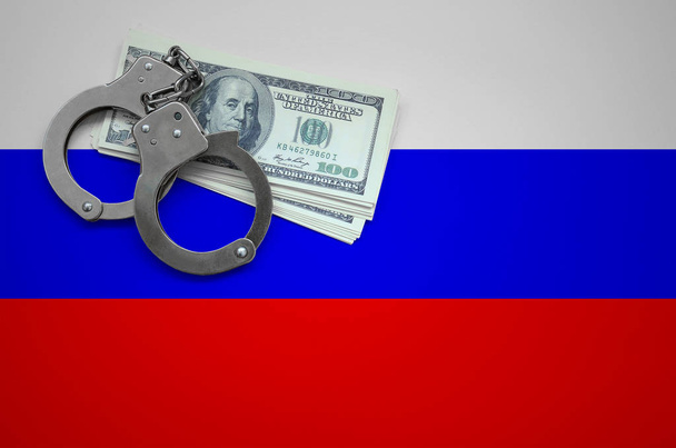 Russia flag  with handcuffs and a bundle of dollars. The concept of breaking the law and thieves crimes. - Photo, Image