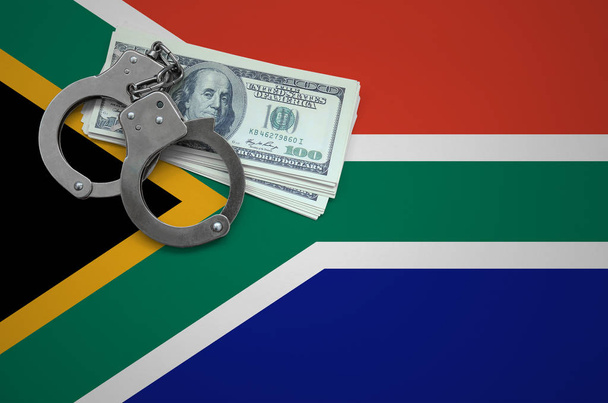Kelepçe ile Güney Afrika bayrak ve a bohça-in dolar. Hukuk ve hırsızlık suçları kırılma kavramı. - Fotoğraf, Görsel