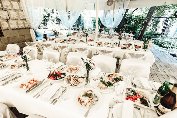 κομψά πολυτελή διακόσμηση πίνακα με λουλούδια και νόστιμο φαγητό, γάμος, γιορτή catering στο εστιατόριο - Φωτογραφία, εικόνα