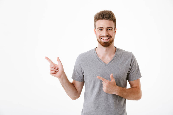 Image of handsome excited happy young man standing isolated over white wall background pointing. - Фото, зображення