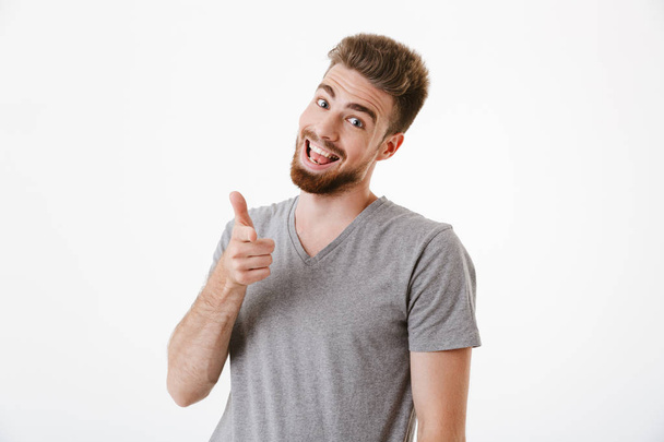 Image of handsome cheerful young man standing isolated over white wall background pointing to you. - Foto, afbeelding