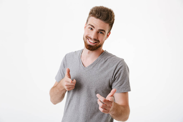 Image of handsome cheerful young man standing isolated over white wall background pointing to you. - Foto, immagini