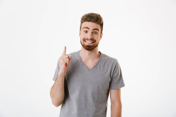 Image of handsome excited smiling young man standing isolated over white wall background have an idea. - Foto, immagini
