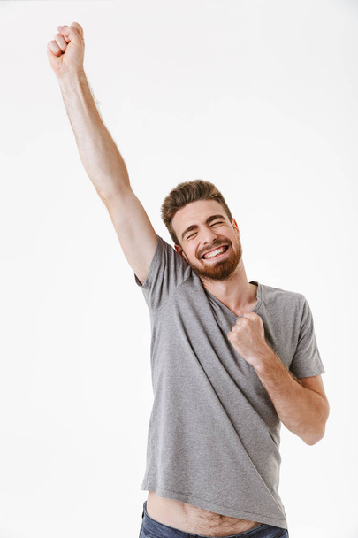 Portrait of a cheerful young bearded man celebrating win isolated over white background - Φωτογραφία, εικόνα