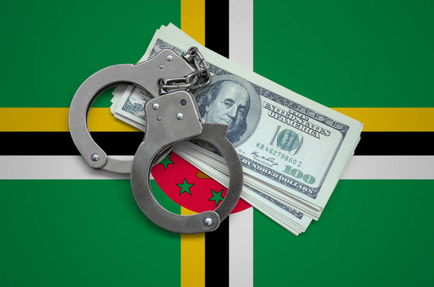 Dominika zászló bilincs és egy köteg-ból dollárok. Pénznem a korrupció az országban. Pénzügyi bűncselekmények. - Fotó, kép