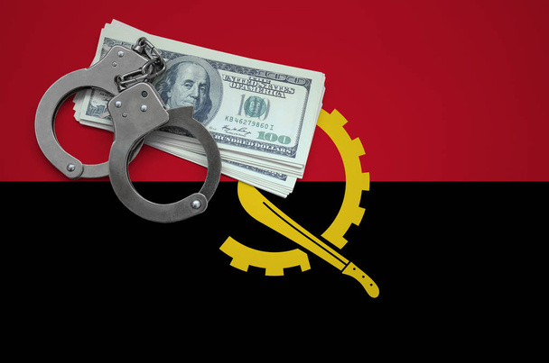 Drapeau de l'Angola avec menottes et un paquet de dollars. Le concept de la violation de la loi et des crimes de voleurs
. - Photo, image