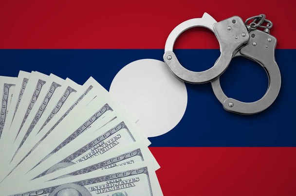 Флаг Лаоса с наручниками и пачкой долларов. Концепция незаконных банковских операций в валюте США
. - Фото, изображение