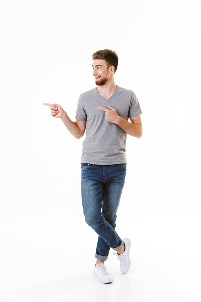 Image of handsome excited happy young man standing isolated over white wall background pointing. - Valokuva, kuva