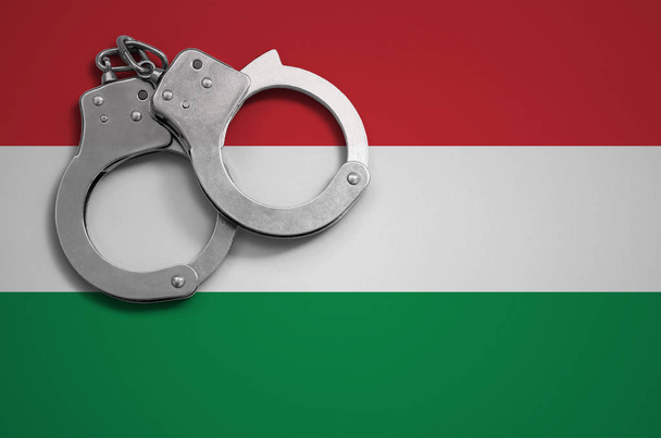 Hongarije vlag en politie handboeien. Het concept van misdrijven en overtredingen in het land. - Foto, afbeelding