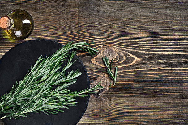 Branches of rosemary on gray wooden table. Rosemary on cutting board. Rustic style, fresh organic herbs. - Photo, Image