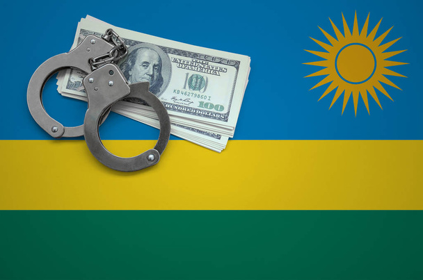 Rwanda flag  with handcuffs and a bundle of dollars. The concept of breaking the law and thieves crimes. - Photo, Image