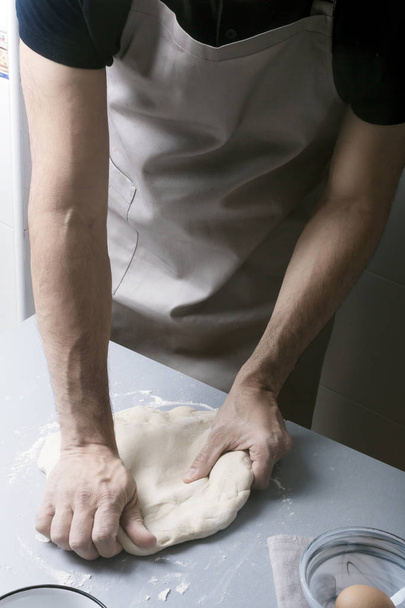 Man on the home kitchen prepares the pizza dough with flour - Foto, imagen