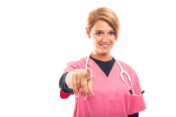Portrait of female vet wearing pink scrub pointing camera isolated on white background with copyspace advertising area - Photo, Image