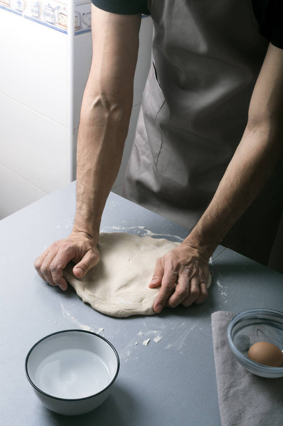 Man on the home kitchen prepares the dough with flour to make organic pan, bread or pasta - Фото, зображення