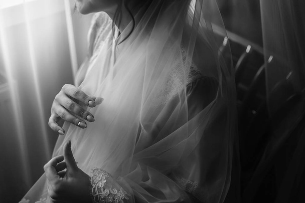 menyasszony esküvő napján reggel. gyönyörű mennyasszonyi portré ablak közelében. szép nő, esküvő, fátyol és jelentő készül. érzéki pillanat - Fotó, kép