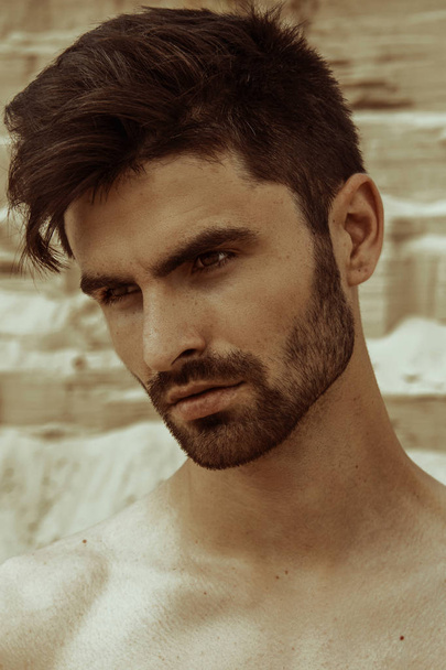 Strong face male model on the nature background with sand and water on the beach on the sunset - Foto, imagen